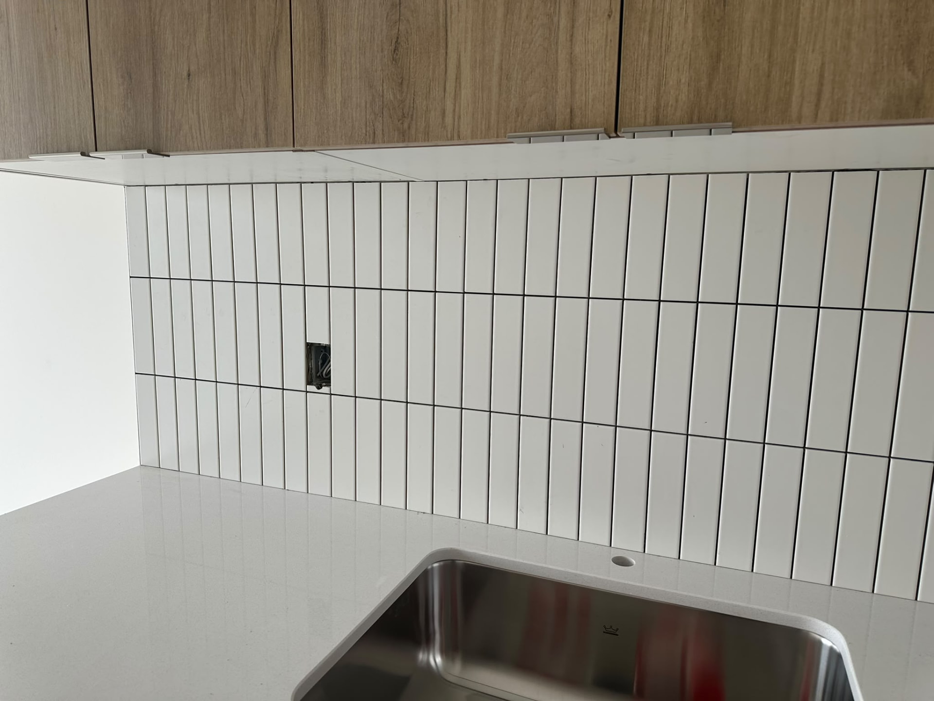 Vertical white tile backsplash beneath wood cabinetry